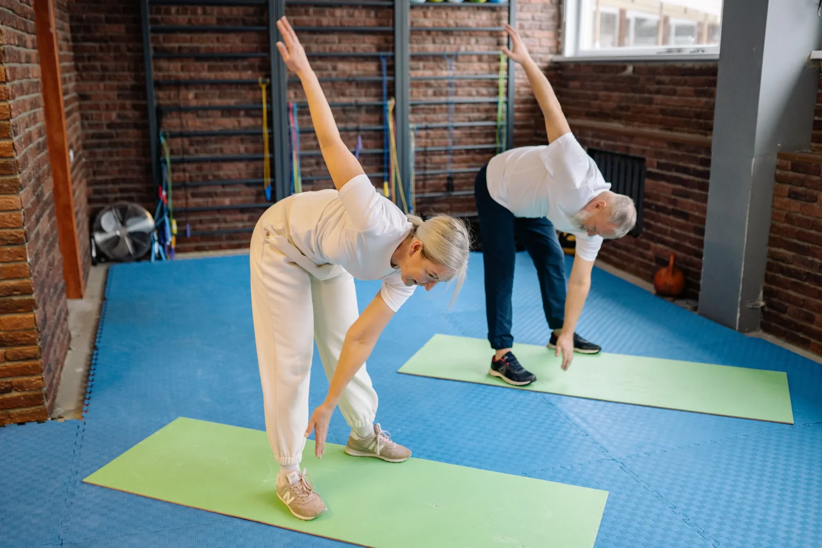 Couple de seniors en étirement latéral du buste pendant une séance de gym douce