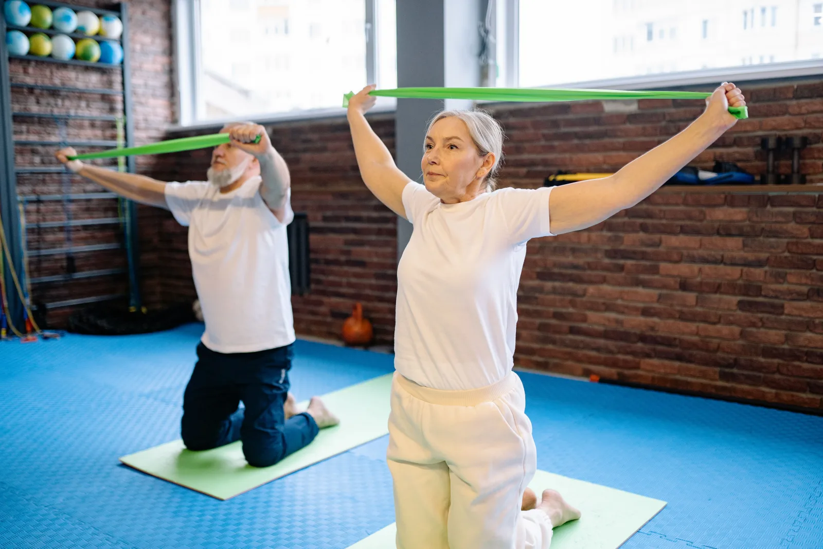 Couple de seniors en séance de gym douce avec élastiques sur tapis de sol