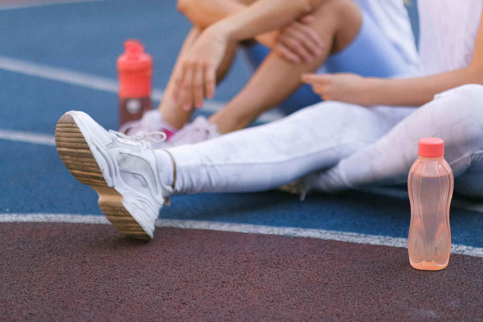 Deux sportifs en pause sur une piste avec leurs gourdes après une séance