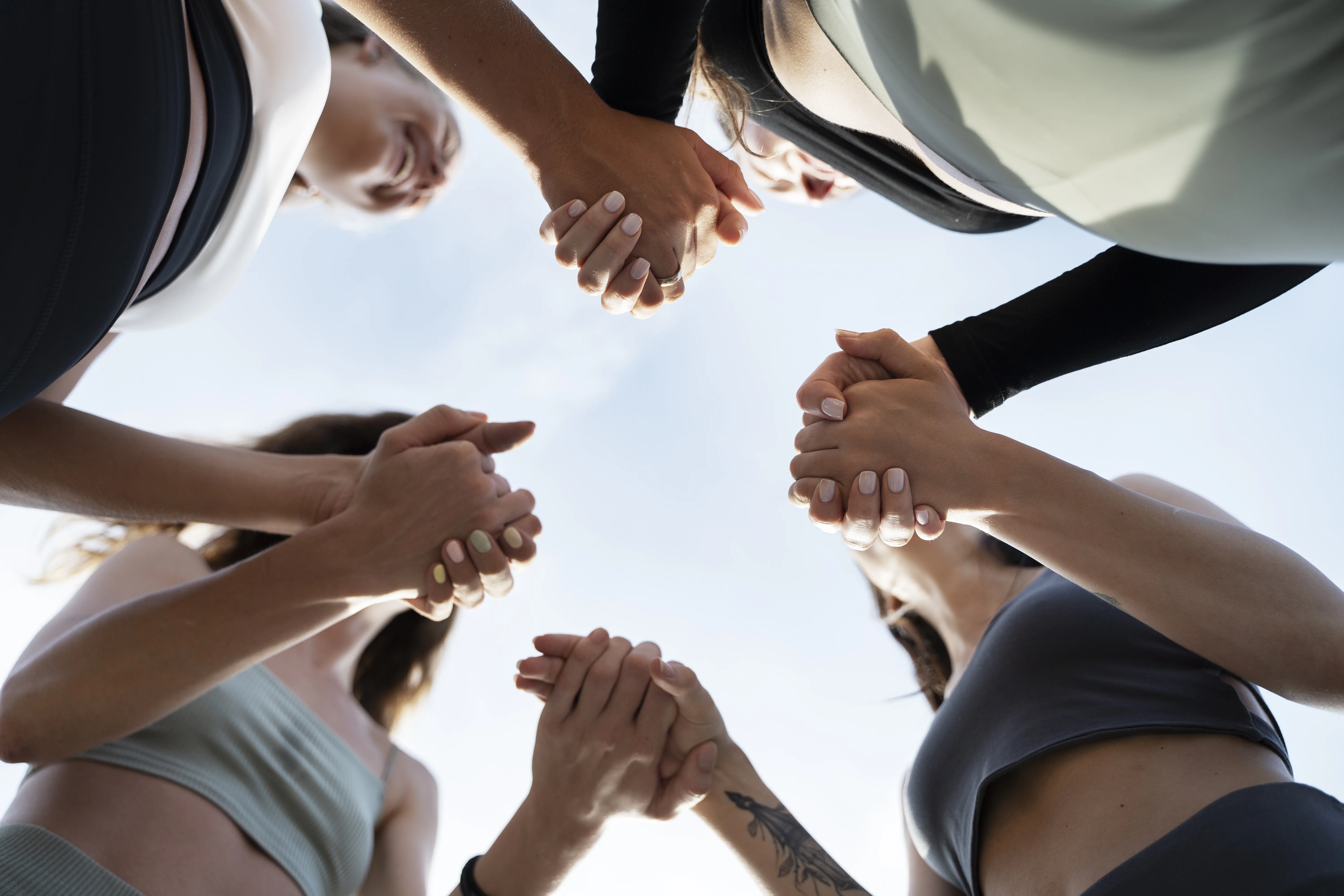 Groupe de participants mains jointes pour symboliser la cohésion du programme collectif